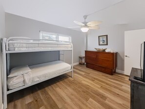 A bunk bed with a ceiling fan, a wooden dresser, and a door with a mirror. - 250 El Matador 2 Bedroom Condo (Fort Walton Beach)