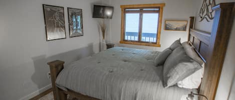 A bedroom with a bed, a bedside table, a window, and wall-mounted artwork.