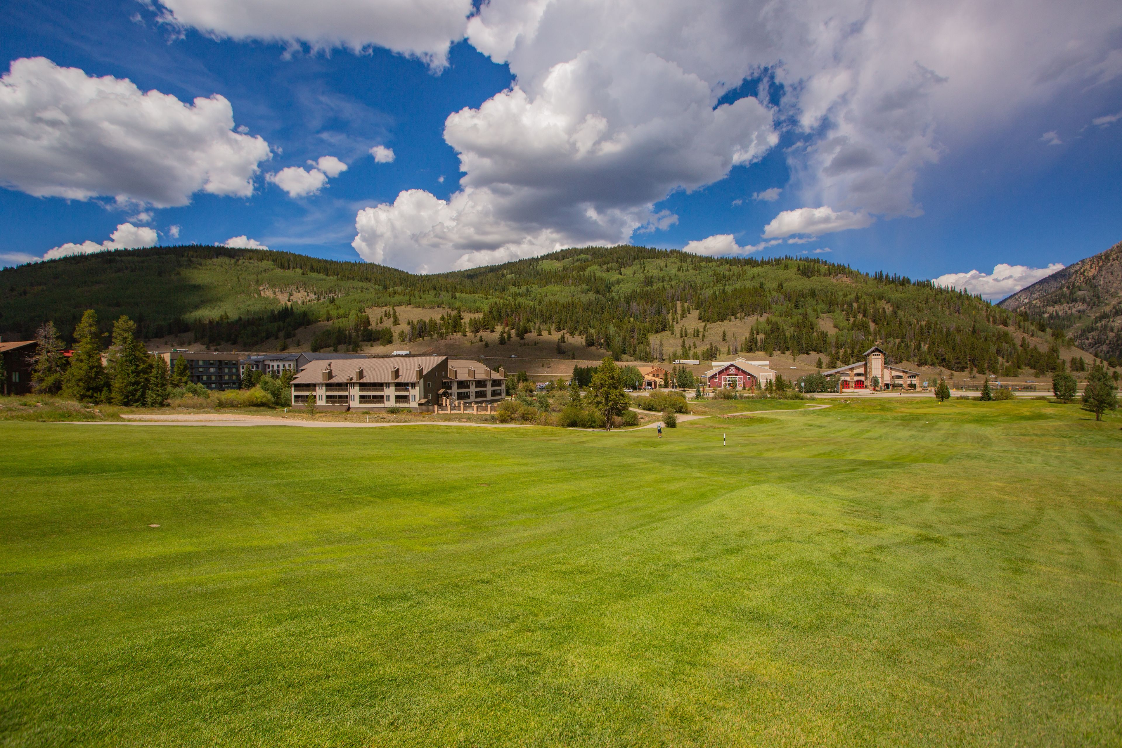 A golf course with a clubhouse and buildings in the background.