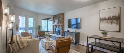 A modern living room with a fireplace, a television, and a dining area.