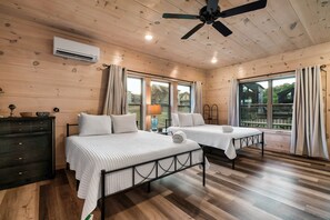 Habitación con dos camas, ventilador de techo y ventanas amplias.