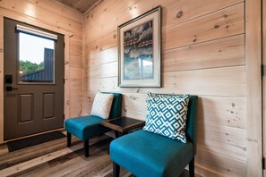 Una habitación con dos sillones azules acolchados, una puerta de madera y un cuadro en la pared.
