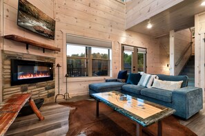Una sala acogedora con chimenea de piedra, un sofá modular azul y una mesa de centro.