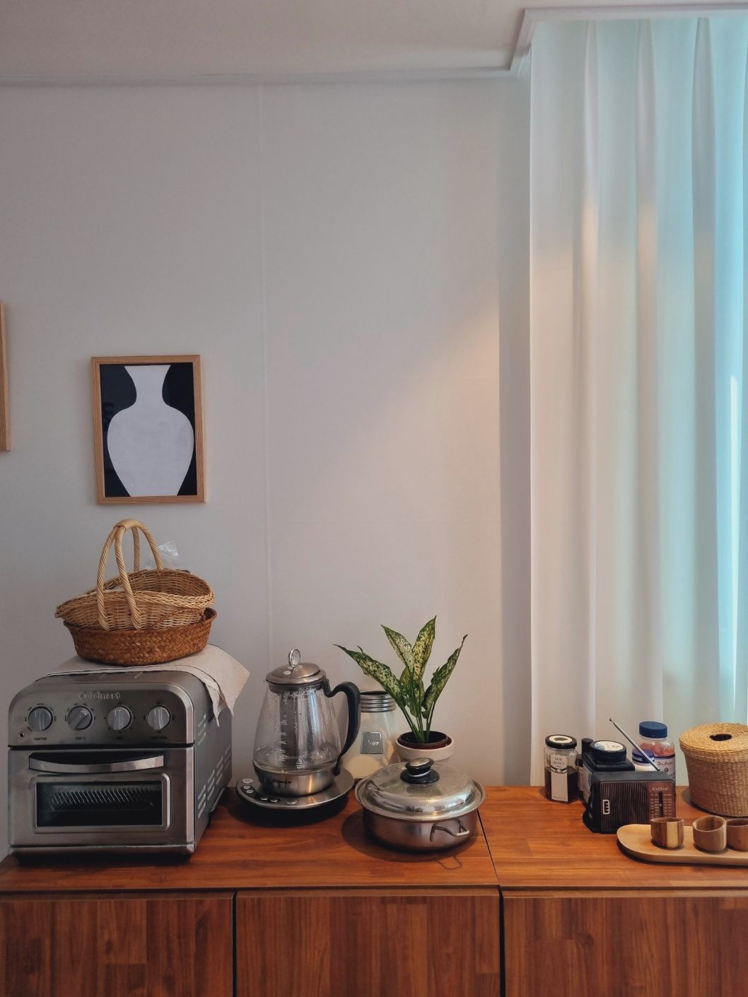 A kitchenette with a toaster, kettle, and a small potted plant.