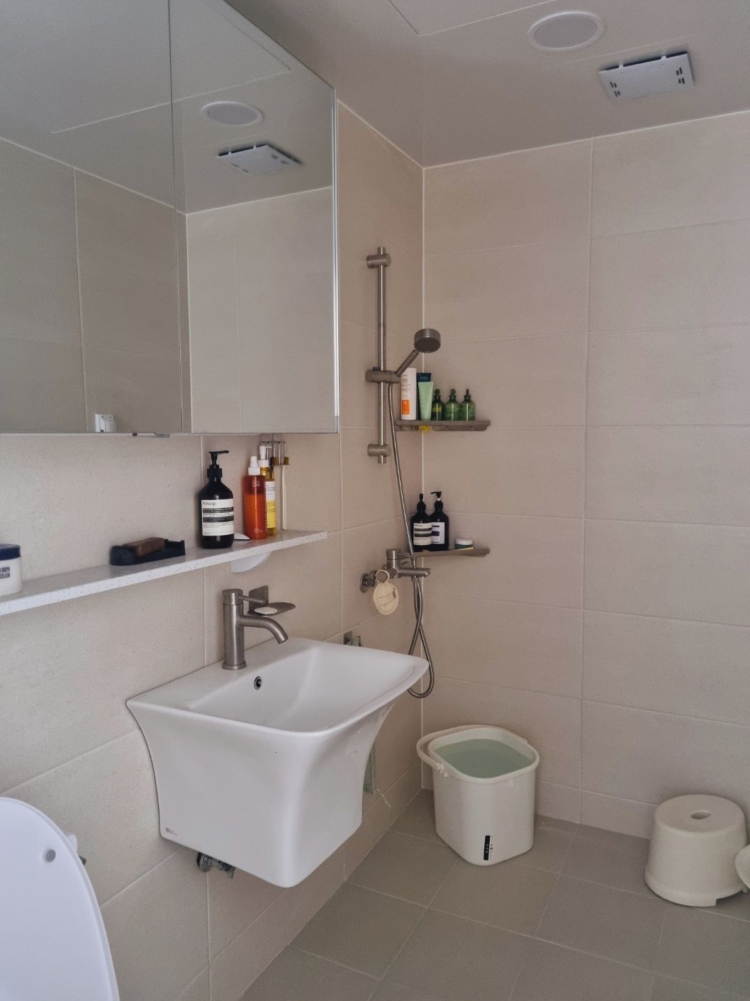 A modern bathroom with a white sink, a toilet, and a shower area.