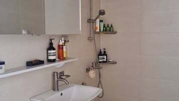 A modern bathroom with a white sink, a toilet, and a shower area.