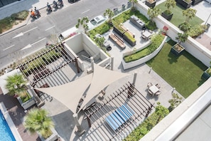 Eine Dachterrasse mit Pool, Sitzbereichen und einem Garten.