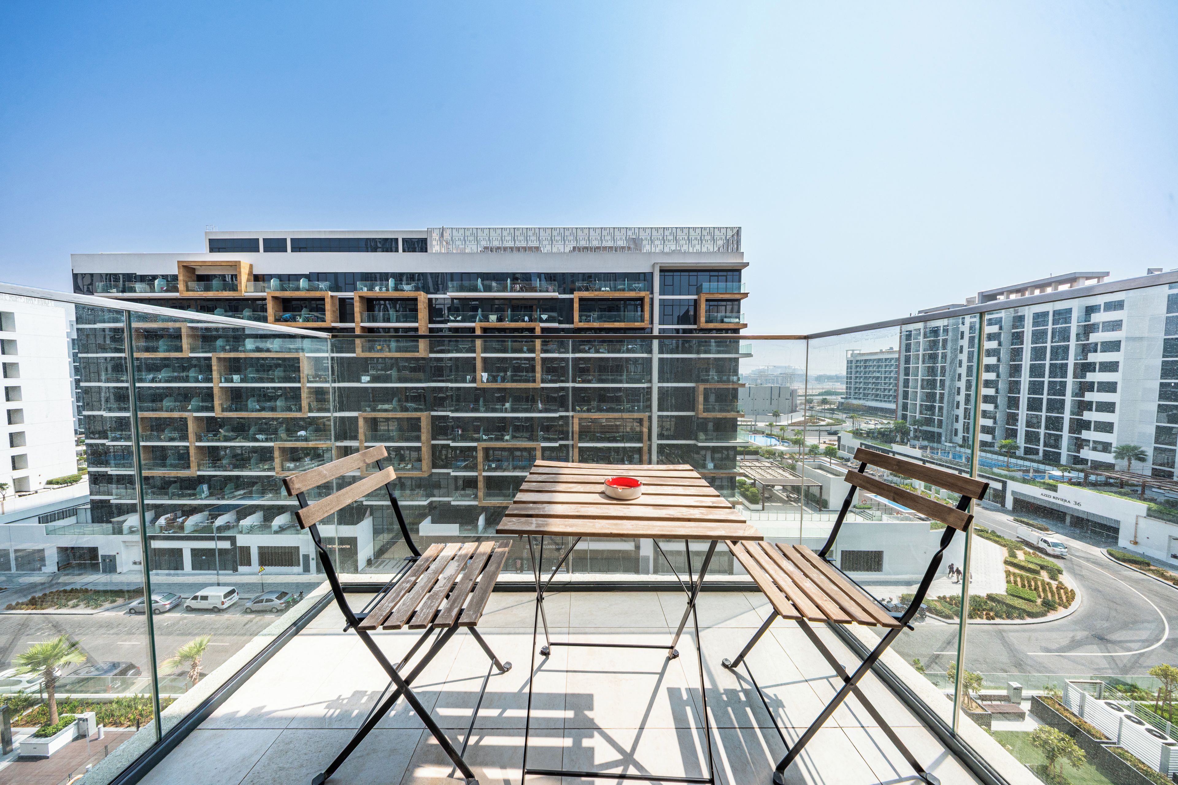 A modern building with a glass facade and wooden benches on the rooftop.