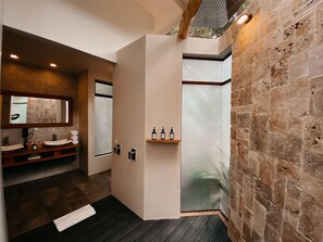 Une salle de bain moderne avec un mur en pierre, une douche en verre et un meuble-lavabo en bois doté d’un miroir.