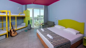 A hotel room with bunk beds, a single bed, a chair, a table, a guitar, and a suitcase. - Be-city Hotel Eilat (Eilat)