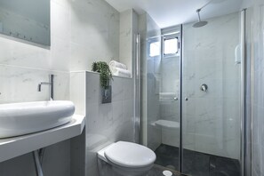 A modern bathroom with a white sink, toilet, and glass-enclosed shower. - Sea Princess Motel (Eilat)