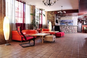 A hotel lobby with a stone wall, red seating, a reception desk, and a view of the cityscape. - Sea Princess Motel (Eilat)