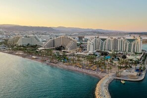 A coastal hotel with multiple high-rise buildings, a beachfront promenade, and a marina. - Sea Princess Motel (Eilat)