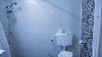 A bathroom with a shower, toilet, and a patterned tile wall.