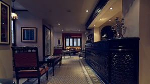 A traditional interior with a long wooden bench, a patterned rug, and a dark wooden cabinet with a geometric design. - Le Riad - Tell A Story (Cairo)