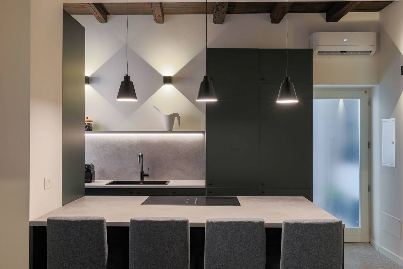 A modern kitchen with a central island, pendant lighting, and a built-in refrigerator.