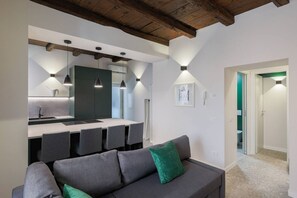 A modern interior with a grey sofa, a kitchen area, and a dining table. - Casa Noce by J&CO Homes (CERNOBBIO)