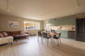 A modern living room with a sofa, coffee table, and dining area. - Luxury apartment on the top floor (Troms)