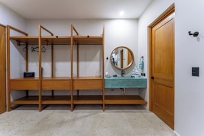 Een kamer met een stapelbed, een ronde spiegel, een wastafel en een deur.