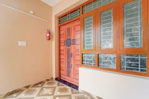 Un pasillo con una puerta de madera, un extintor y baldosas de suelo con diseños.
