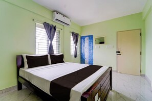 A room with a bed, an air conditioning unit, a door, and a window with curtains. - Collection O MKU Madurai (Madurai)