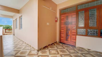 A corridor with patterned flooring, a wooden door with glass panels, and a fire extinguisher mounted on the wall.
