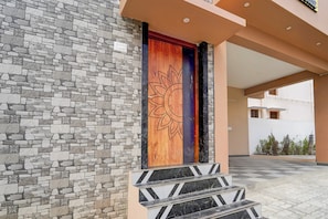 Fachada de un edificio con pared de piedra y puerta de madera con un diseño de sol.