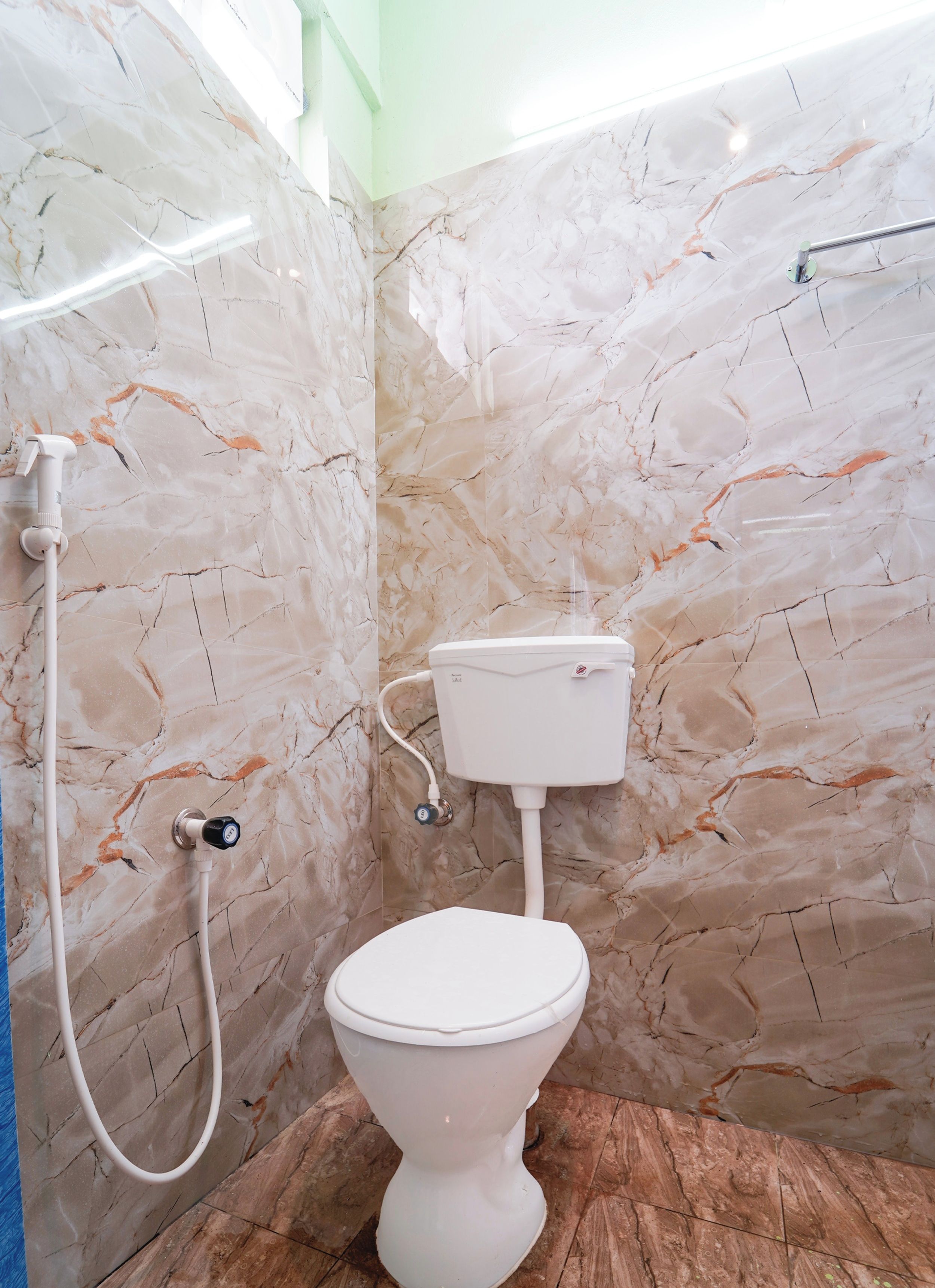 A bathroom with a toilet, a shower, and marble walls.