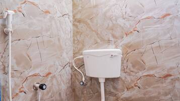 A bathroom with a toilet, a shower, and marble walls.