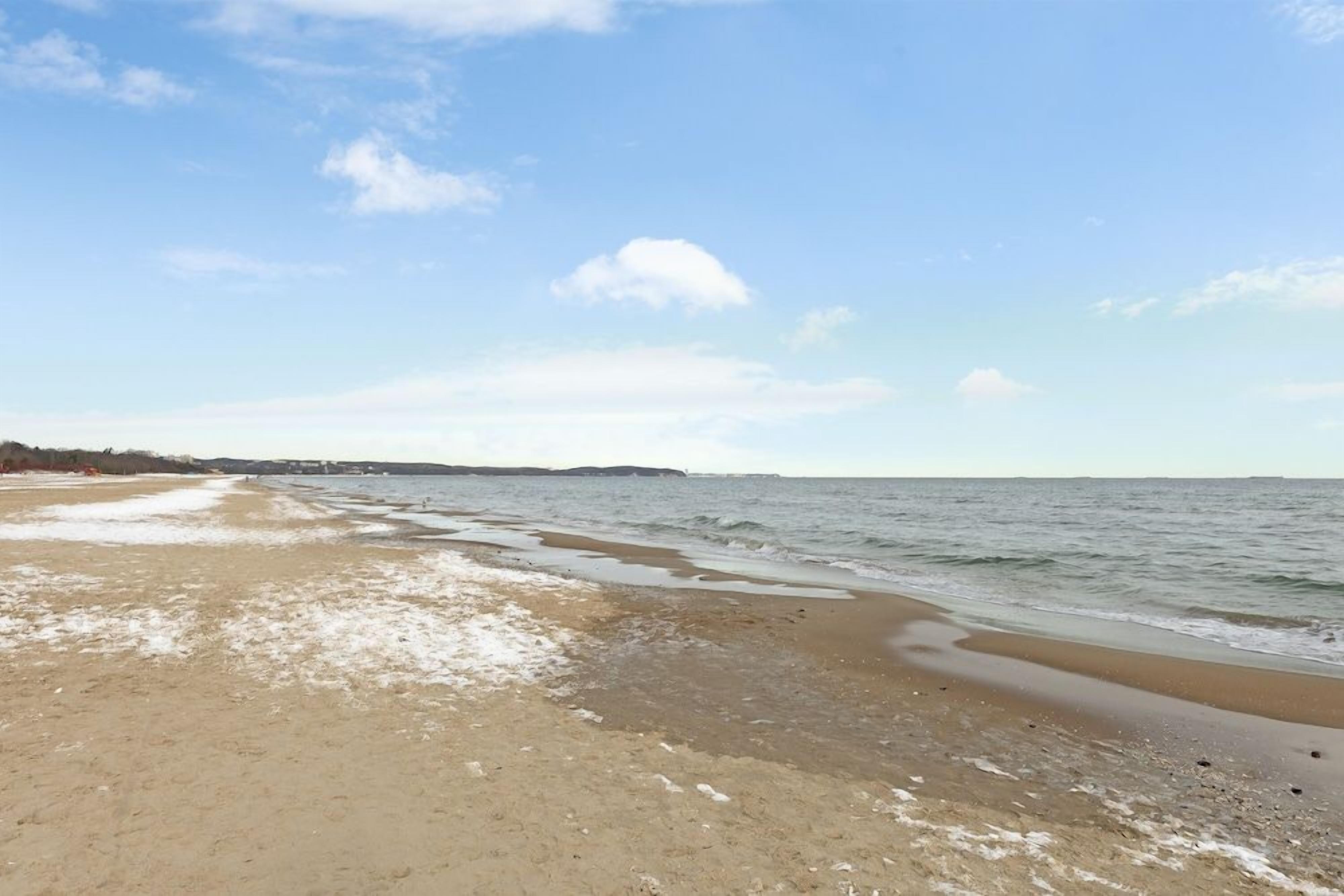 Een strand met een brede zandkust en rustig water.