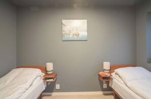 A room with two single beds, a nightstand with a lamp, and a painting on the wall. - Spacious and elegant apartment (Troms)