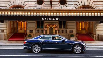 A luxury car parked in front of a grand building with a sign reading 'STREGIS'.