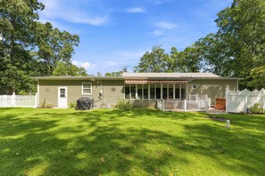 Ein Bungalow mit Veranda, überdachtem Patio und umzäunter Rückseite.