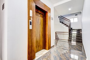 A modern interior with a wooden door, a phone, and a staircase. - Collection O Munnar (Devikolam)