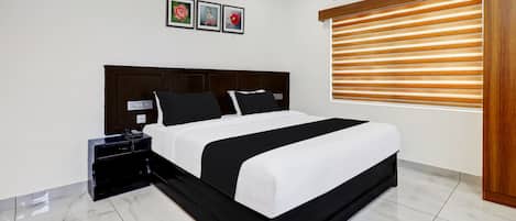 A modern bedroom with a large bed, a bedside table with a phone, and a wall-mounted air conditioner.