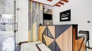 Een receptiebalie met een modern design, een bevestigde televisie en een bord dat bedrijfsdiensten aangeeft.