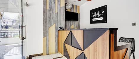 Un mostrador de recepción de diseño moderno, con un televisor montado y un cartel que indica servicio de la empresa.