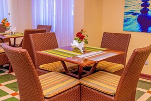Comedor con sillas de mimbre y una mesa dispuesta para cuatro.