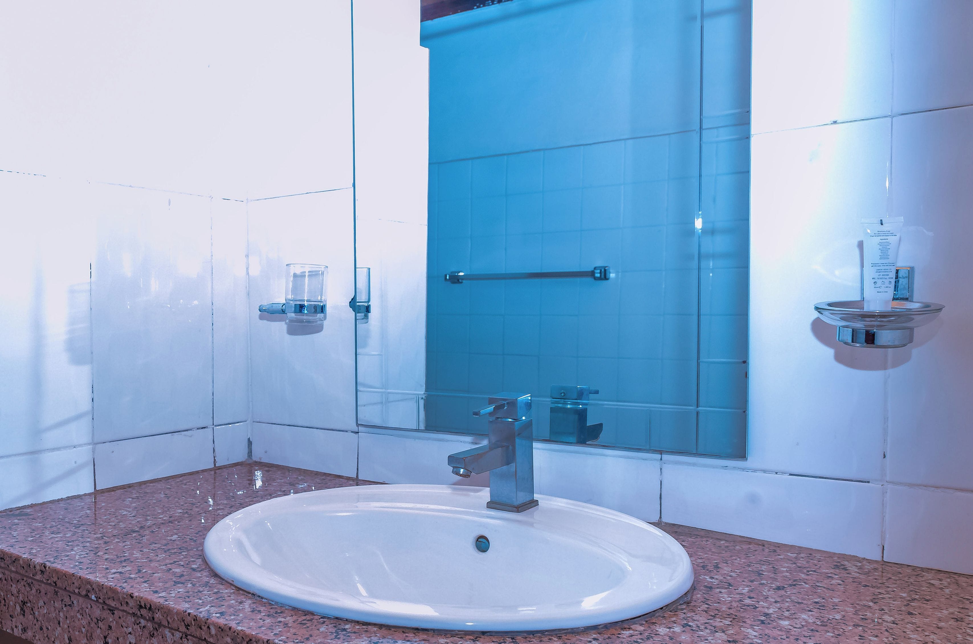 Un baño con un lavamanos blanco, un espejo y una pared con azulejos azules.