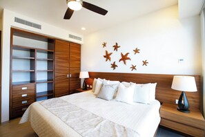 A hotel room with a bed, nightstands, a ceiling fan, starfish wall decor, and a wooden wardrobe. - Alamar 903 ptv vallarta  · Ocean View Terrace & Grill | Alamar Luxury Stay (Cruz de Huanacaxtle)