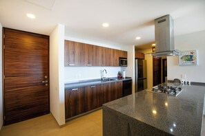 A modern kitchen with wooden cabinets, stainless steel appliances, and a granite countertop. - Alamar 903 ptv vallarta  · Ocean View Terrace & Grill | Alamar Luxury Stay (Cruz de Huanacaxtle)