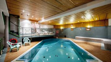 Ein Hallenbad mit Holzbalkendecke, Liegestühlen und einem sichtbaren Rettungsring.