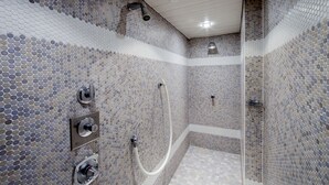 Un baño moderno con diseño de mosaico, zona de ducha y panel de control visible para el agua y la temperatura.