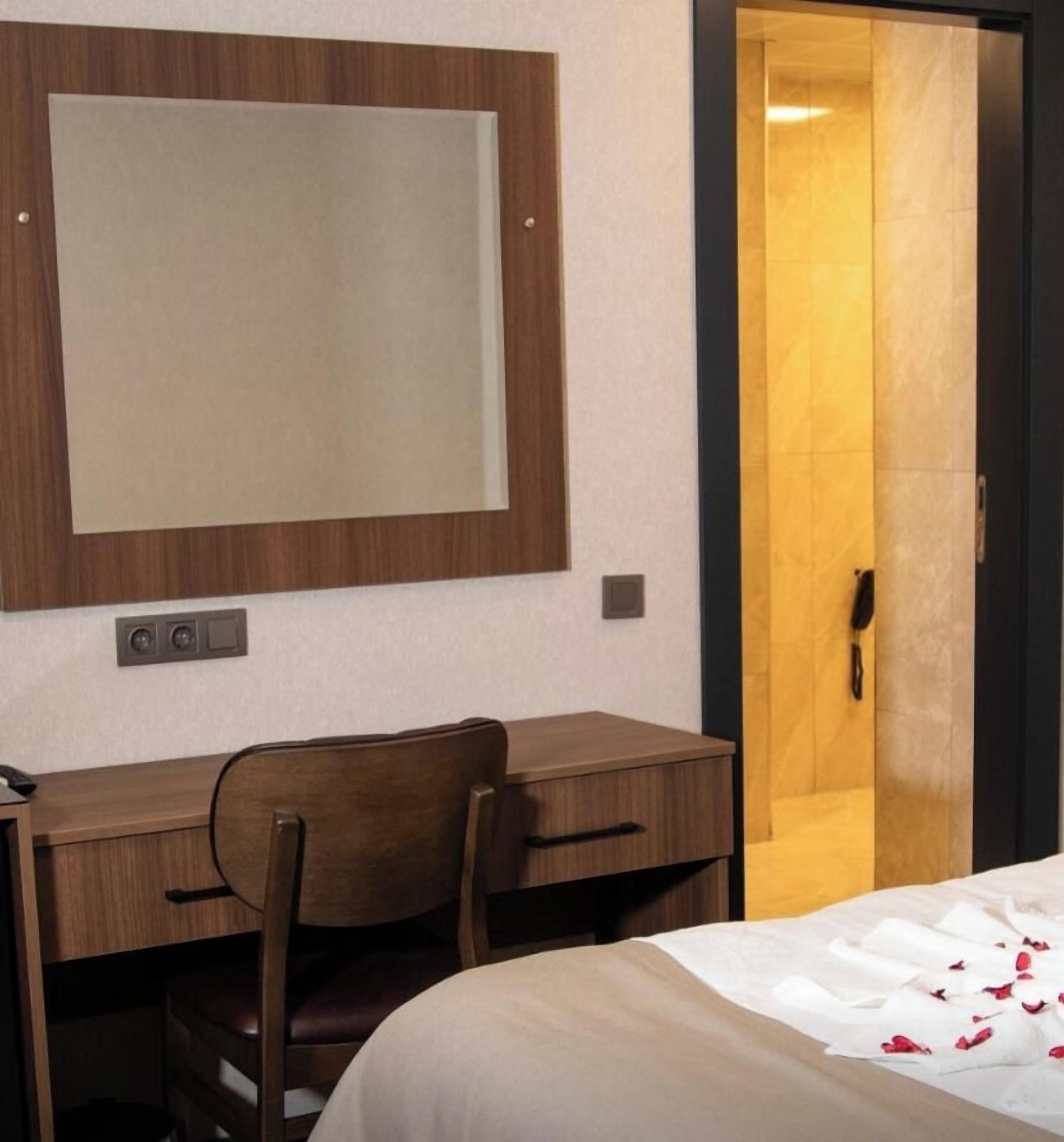 Ein Hotelzimmer mit einem Bett, einem Schreibtisch, einem Stuhl, einem großen Spiegel und einer Tür zu einem Badezimmer.
