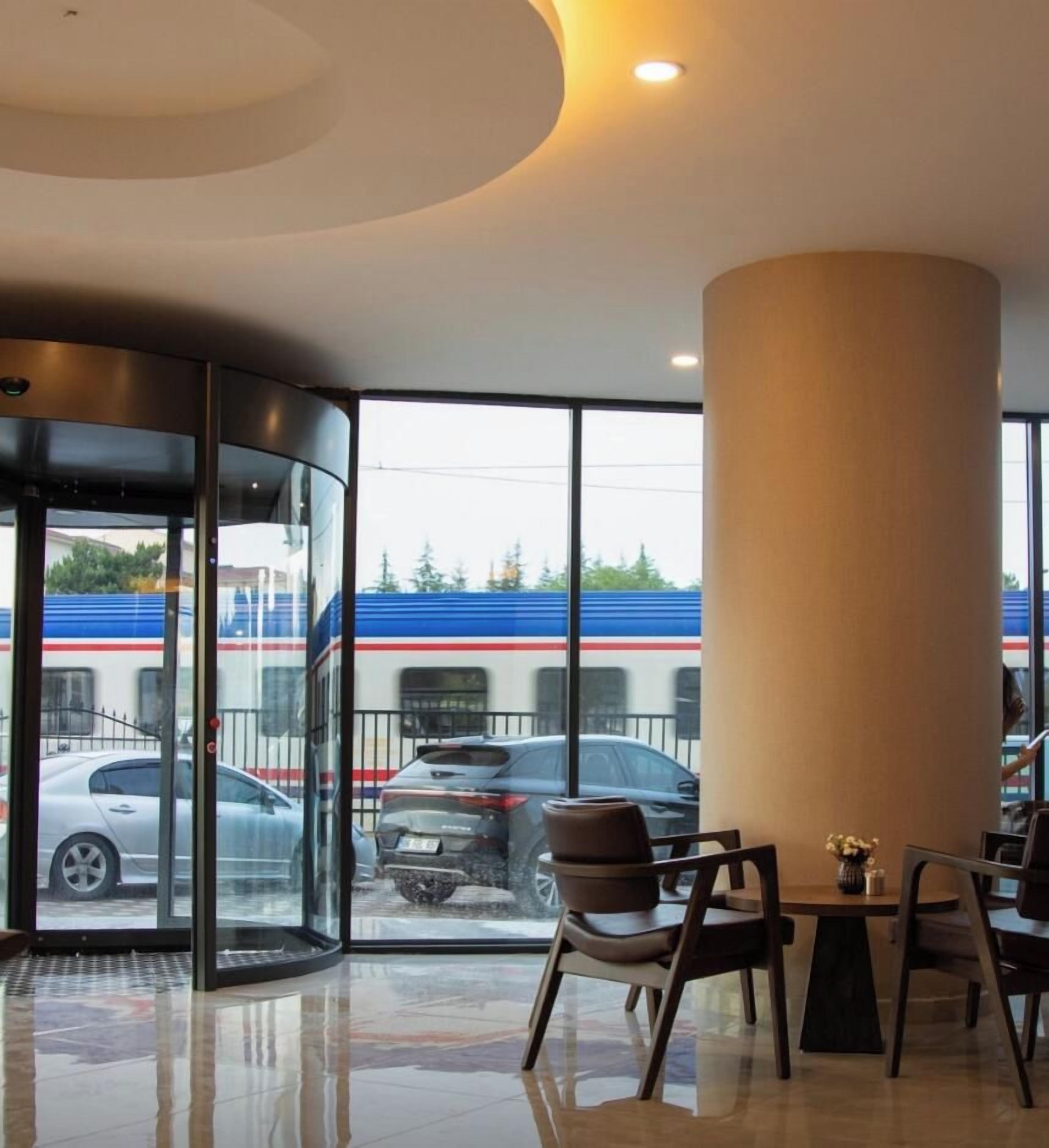 Eine Hotelhalle mit Glastür, einer großen Säule und Blick auf einen Zug.