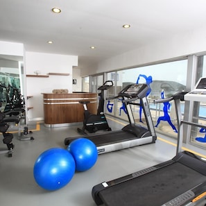 A gym with exercise equipment, a reception desk, and large windows. - Aktur Residence (Bodrum)
