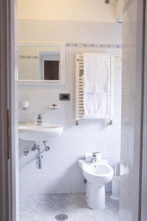 A bathroom with a sink, bidet, and towel rack.