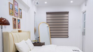 Un dormitorio con cama, mesita de noche, lámpara y ventana con persianas.