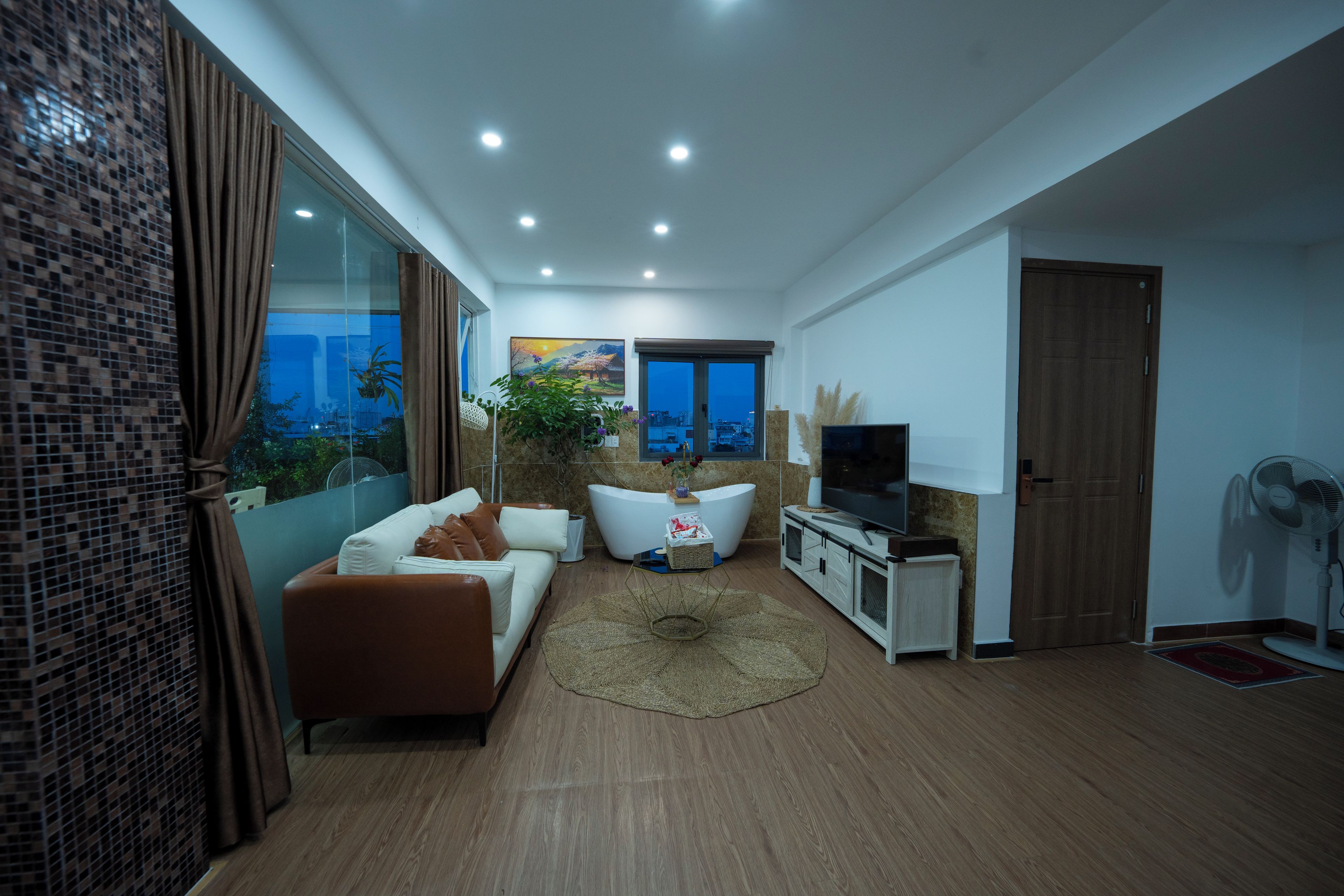A modern living room with a sofa, a TV, and a large window.