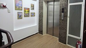 Un ascensor moderno con pantalla digital, extintor de incendios y detector de humo instalado en la pared.